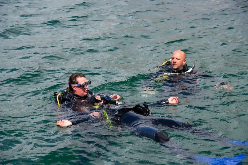 Búvárok a vízfelszínen sötét ruhában – Drift és Dry Suit Diver